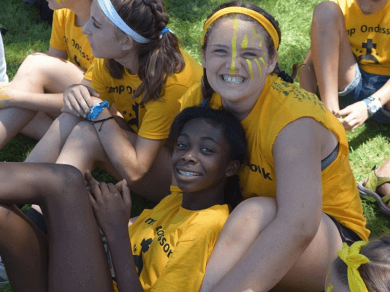 Four girls smiling in yellow shirts.