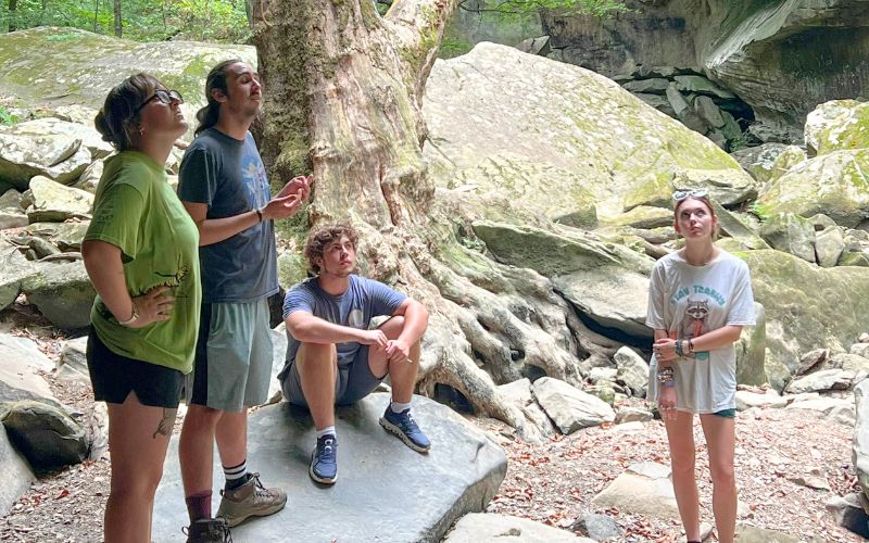 Group exploring rocky forest area together.