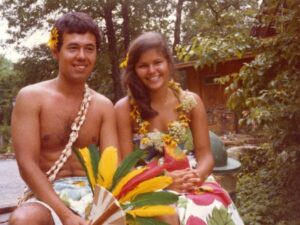 Couple in Hawaiian attire with flowers.