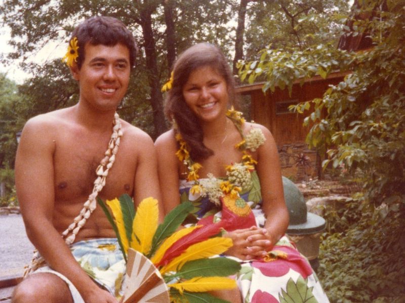 Couple in Hawaiian attire with flowers.