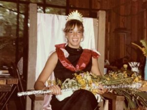 Smiling woman crowned in a chair with flowers.