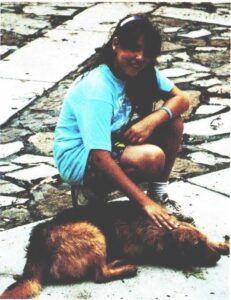 Girl petting her brown dog outdoors.