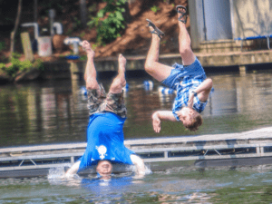 Two men jumping off a dock into water.