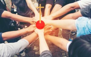 Hands joined in unity around cross