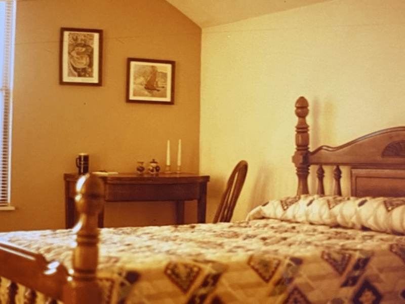 Wooden bed with patterned quilt in bedroom.