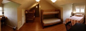 A room with bunk beds and a desk.