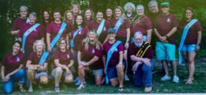 Group of people wearing maroon shirts and sashes.