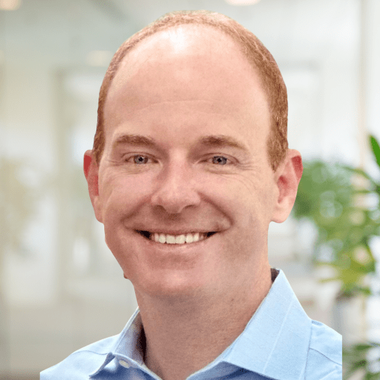 Smiling man in blue shirt headshot.