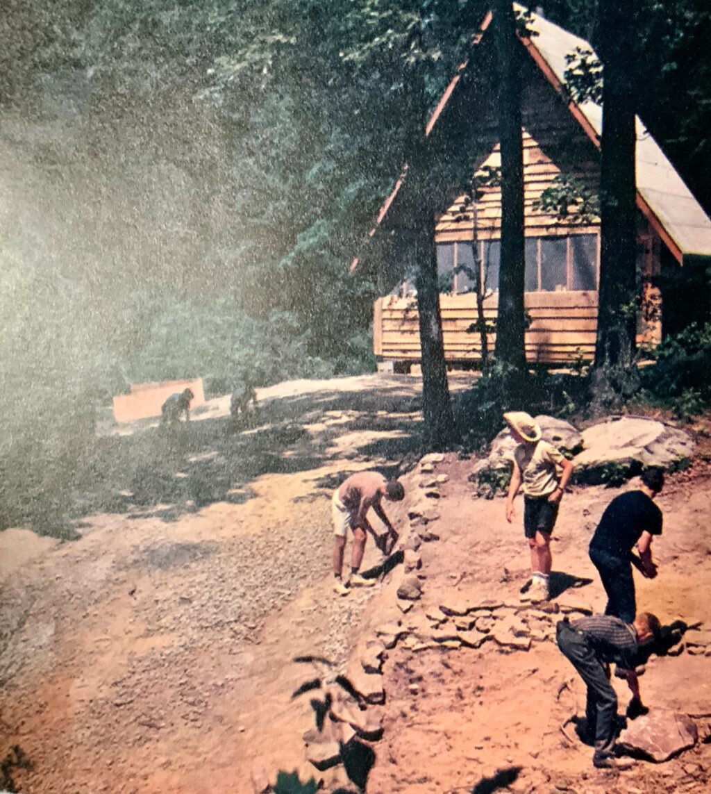 Kids building a stone wall near a cabin.