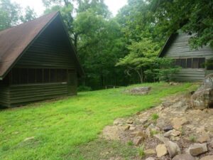 Two rustic cabins in a wooded area.