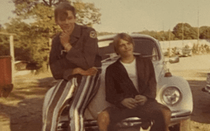 Two teens posing on vintage VW Beetle.