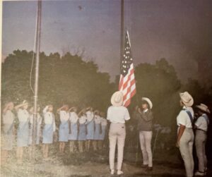 Girls salute US flag at ceremony.