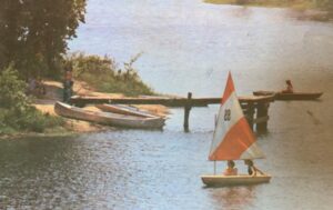 Sailboat and canoes at lakeside dock.