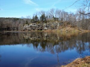 Lake reflecting trees and cliff face.