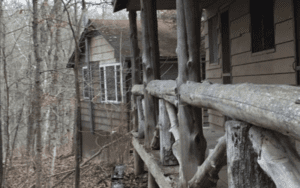 Wooden porch railing with cabin in background.