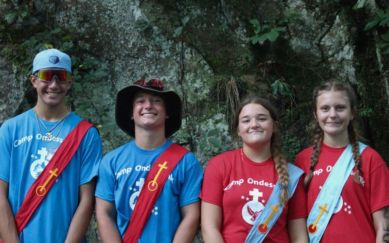 Four campers in camp shirts and sashes