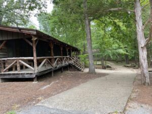 Wooden cabin with porch in wooded area.