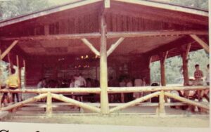 Wooden pavilion with people gathered inside.