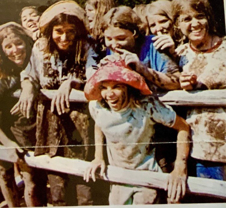 Smiling girls covered in mud, fence.