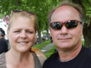 Couple smiling in sunglasses outdoors.
