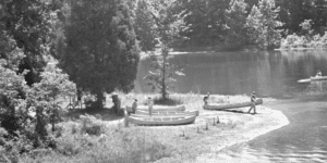 Canoes by lakeshore; people carry boats.
