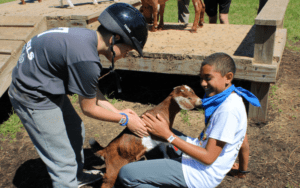 Unrestricted Giving Provides Unlimited Opportunities- Two Campers playing with a baby goat