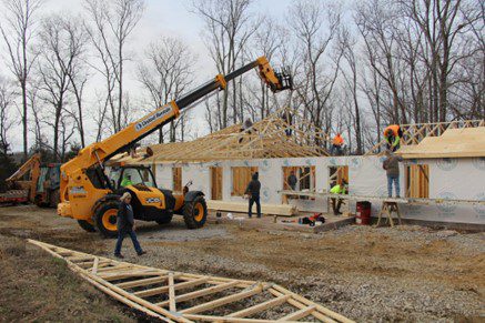 Yellow forklift lifting beams at construction site.