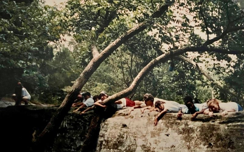 People lying on a large rock outdoors.