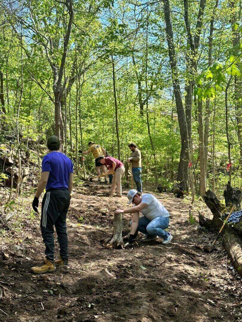 Five men working on a trail in the woods.
