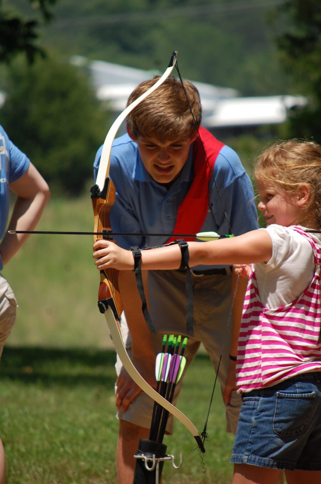 Child practicing archery with instructor