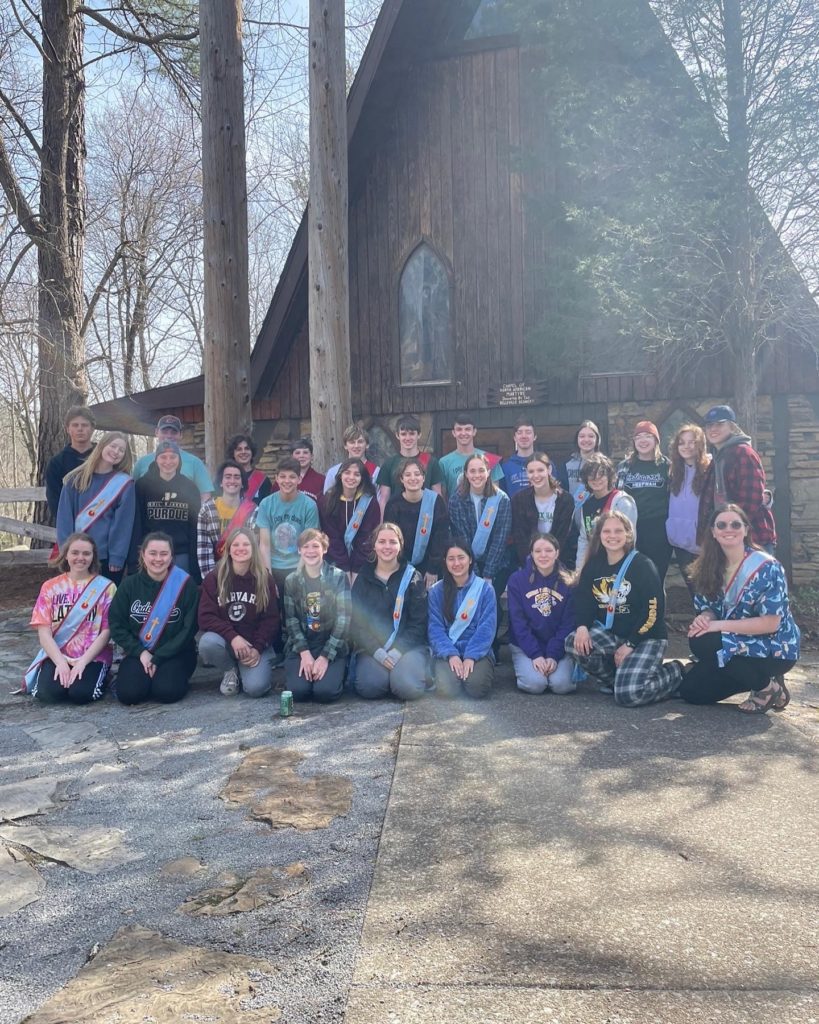 Youth retreat group outside wooden A-frame chapel